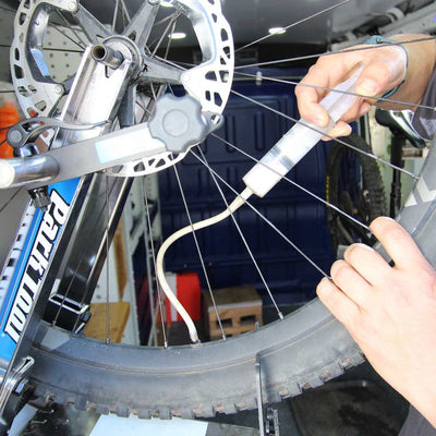 mecanico de bicicletas a bordo de taller movil chum, relaliza inyeccion con recarga de liquido sellante tubeless a bordo de taller movil chum