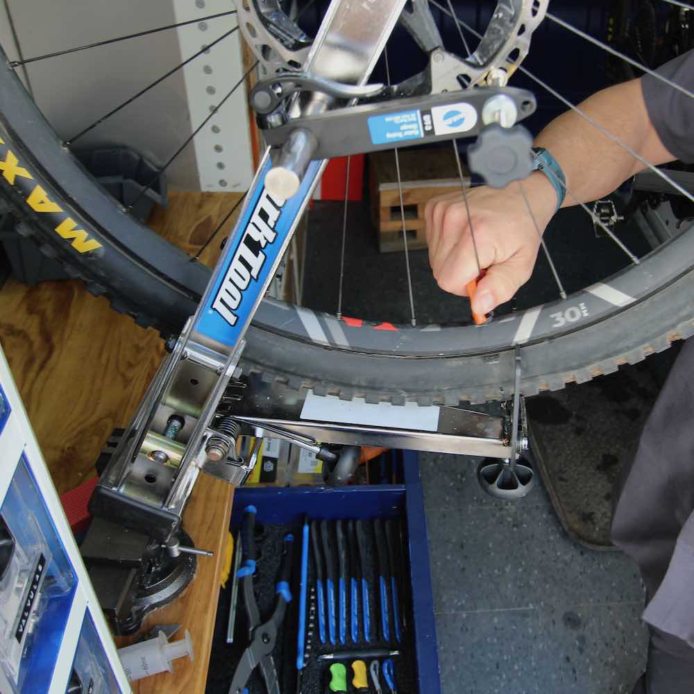 mecanico de bicicletas realiza centrado de bicicleta a bordo de taller movil chum