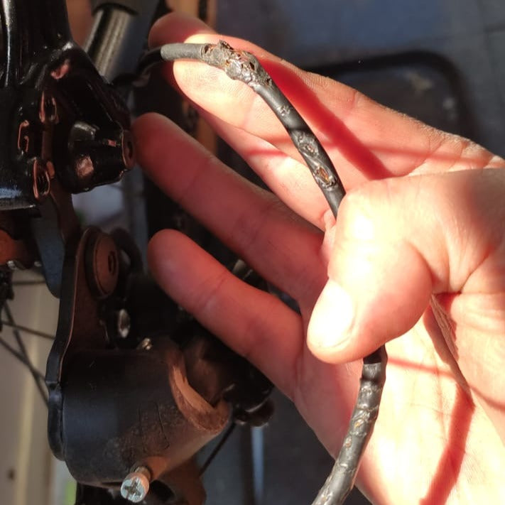 funda de cable de cambio de bicicleta dañada , antes de ser reemplazada a bordo de taller chum