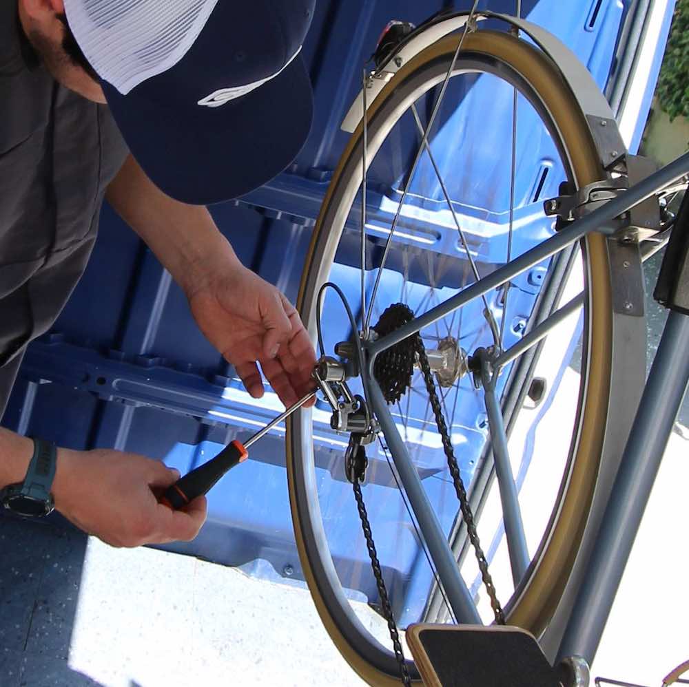 mecanico de bicicleta regula o sincroniza cambio trasero durante mantencion a bordo de taller movil chum